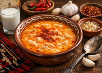 Традиционна българска шкембе чорба, сервирана с чесън, люта чушка и чаша прясно мляко