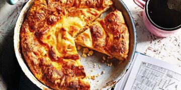 Традиционна баница за Сирни Заговезни на празнична българска трапеза с халва и червено вино